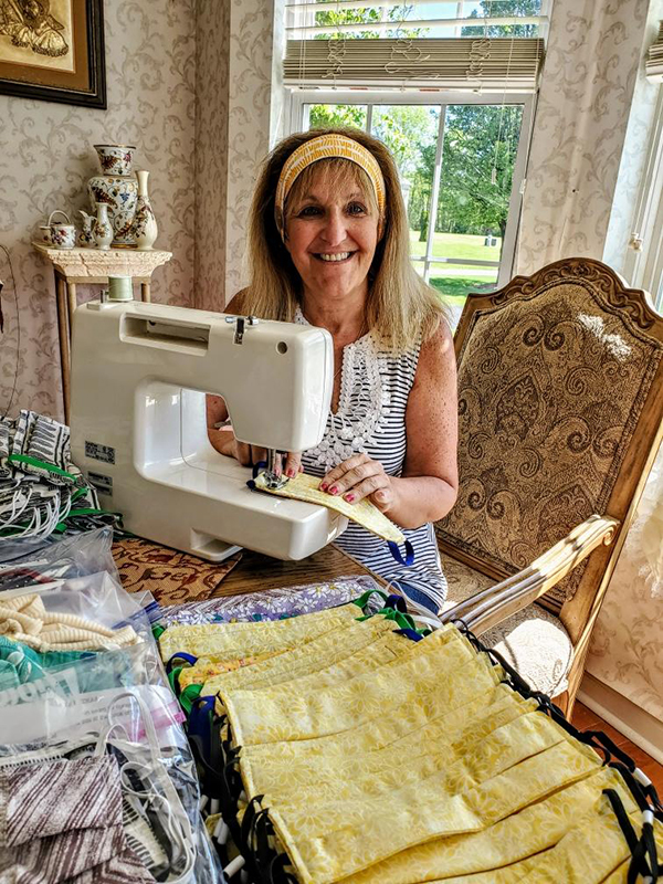 Volunteer at a sewing machine with rows of handmade masks