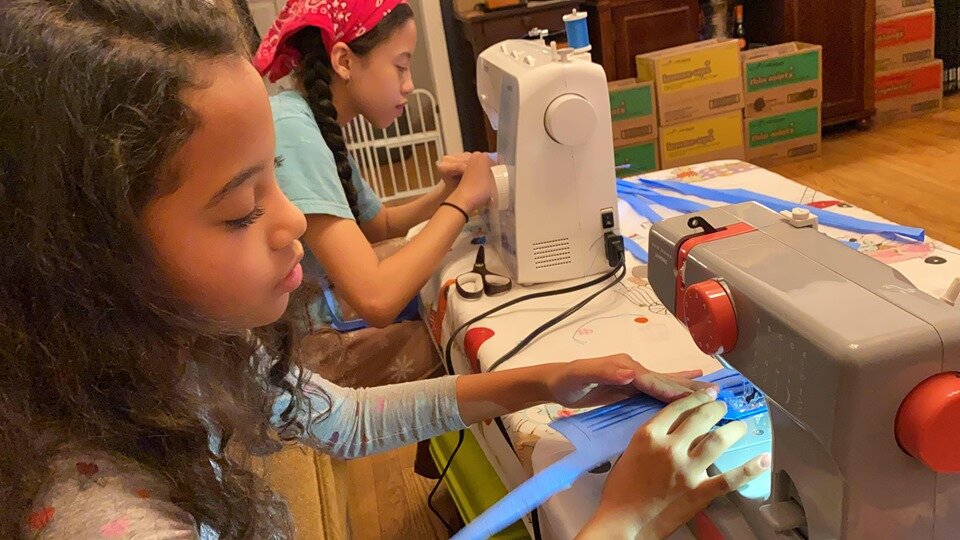 A young volunteer sewing colorful fabric at a sewing machine